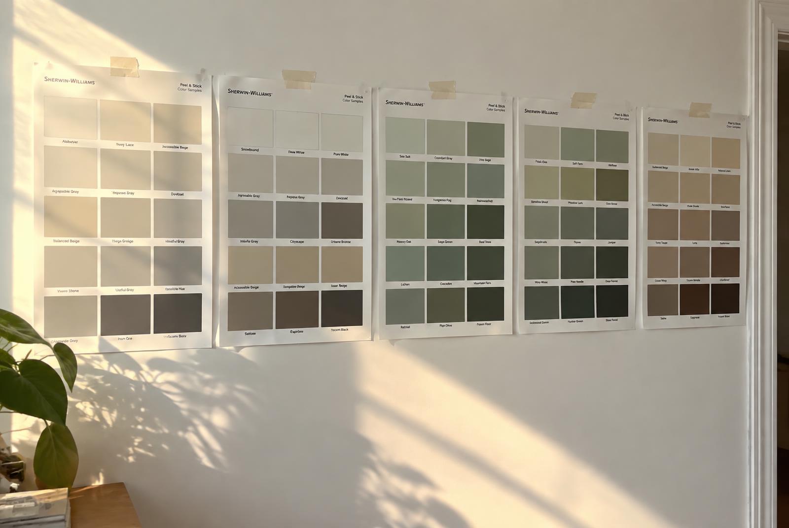 Large peel-and-stick paint color sample sheets taped to an interior wall in afternoon sunlight